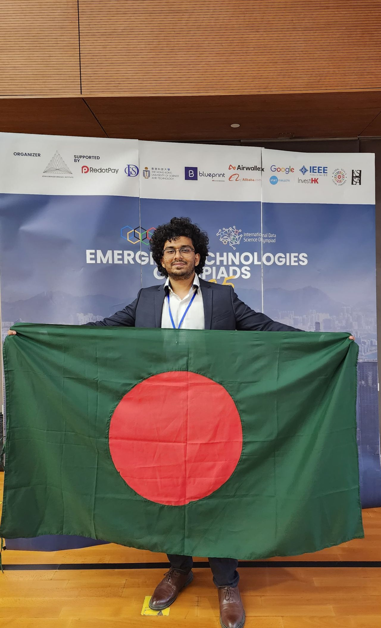 Sakib Ahmed Shanto proudly holding Bangladesh flag at IBCOL 2025 International Blockchain Olympiad in Hong Kong representing Team BIKchain and Islamic University of Technology